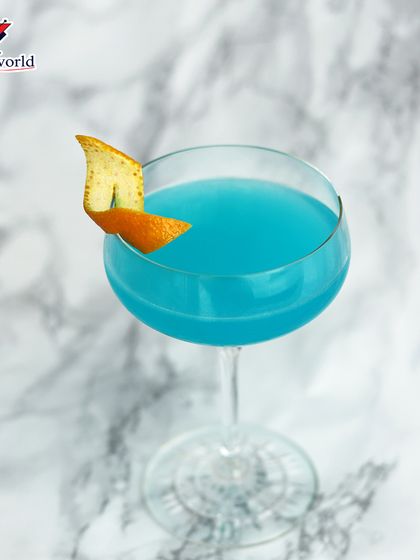 A stunning blue cocktail with an orange peel twist, set against a clean marble background. The vibrant color and minimalist garnish create a modern and sophisticated look.