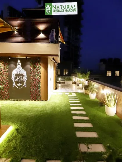 The same Gwal Pahari project at night, with carefully placed lights illuminating the pathway, planters, and decorative wall panels.
