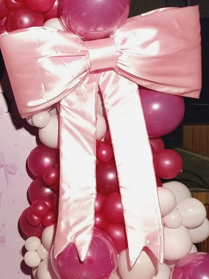 The star of the show! A detailed look at the large, beautifully crafted pink satin bow that makes this birthday decoration so unique and memorable.