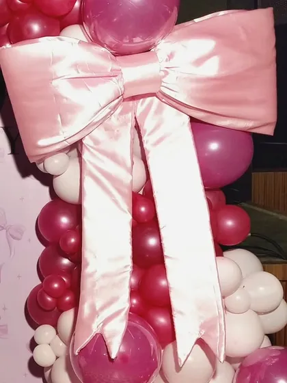 The star of the show! A detailed look at the large, beautifully crafted pink satin bow that makes this birthday decoration so unique and memorable.