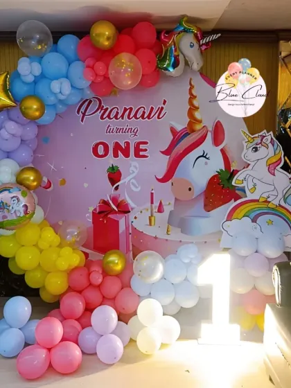 A close-up of a unicorn-themed first birthday backdrop, showing the custom print and colorful balloon details.