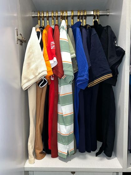 Even a small section of a wardrobe can be highly functional. Here, we have organized men's polo shirts on matching hangers for a clean and accessible setup.