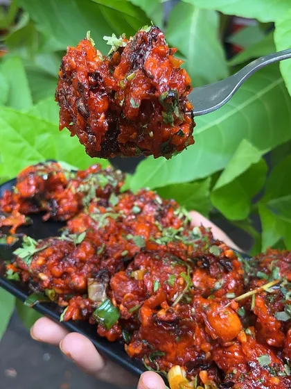 A bite of my Veg Crispy, showing the perfectly fried vegetables coated in a spicy and tangy sauce.