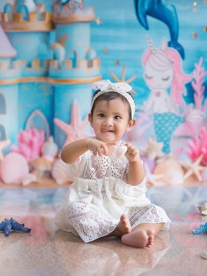 Reaching out from her underwater kingdom. This little girl is having so much fun in her mermaid-themed session, surrounded by shells and starfish.