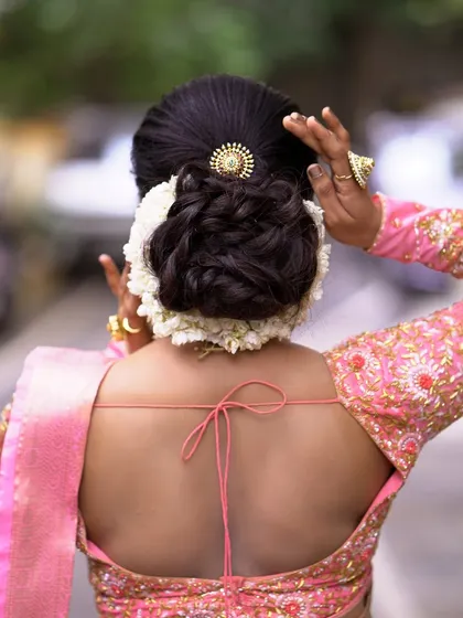 A classic floral bun, perfect for a Muhurtham or reception look. I've created a neat, voluminous bun and encircled it with fresh white jasmine (Mallige), ensuring the flowers are stitched in place so you can move freely without any worry.