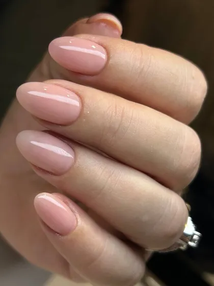 A soft, sheer pink manicure on beautifully shaped oval nails. This is the epitome of a clean, healthy, and natural look, enhanced with a glossy finish.