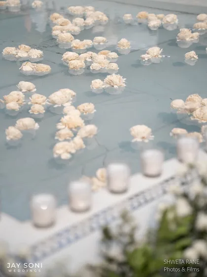 A close-up of the flowers floating in the pale blue water of the pool, a simple yet incredibly effective and beautiful decor detail.