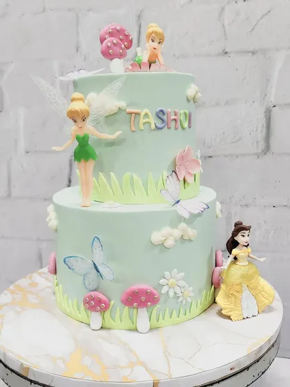 A cake fit for a little princess, featuring Tinkerbell and Belle. This two-tiered design creates a magical fairy garden scene with handcrafted mushrooms, flowers, and butterflies.
