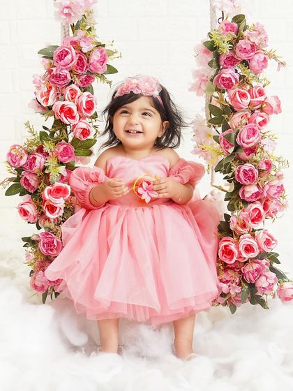 A happy princess on her floral swing. Her bright smile and the beautiful pink roses create a joyful and enchanting portrait.