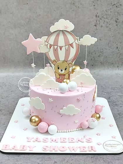A pink hot air balloon themed cake for Yasmeen's baby shower. This adorable cake features a teddy bear, clouds, and stars.
