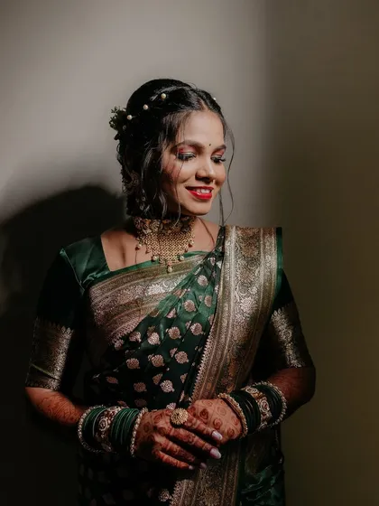 A portrait of the bride, Priya, in her stunning green and gold saree, looking radiant on her engagement day.