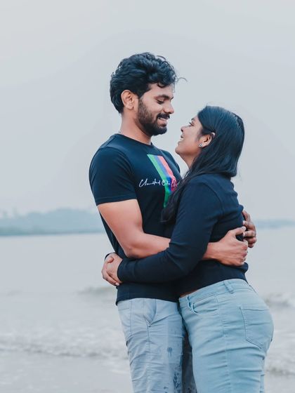 A candid photo of a couple sharing a look of love and laughter during their casual pre-wedding shoot on the beach.