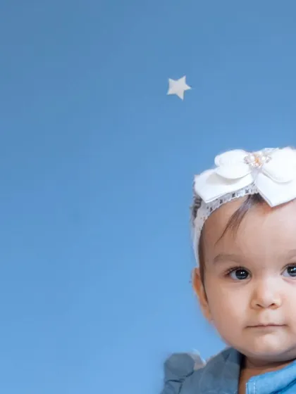 A simple and sweet studio portrait against a blue background with star decals. This setup creates a dreamy, sky-like theme for a baby photoshoot.