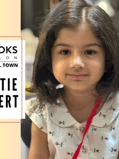 A cutie alert! This little girl is all smiles after her fresh haircut, showing off her new, neat bob.