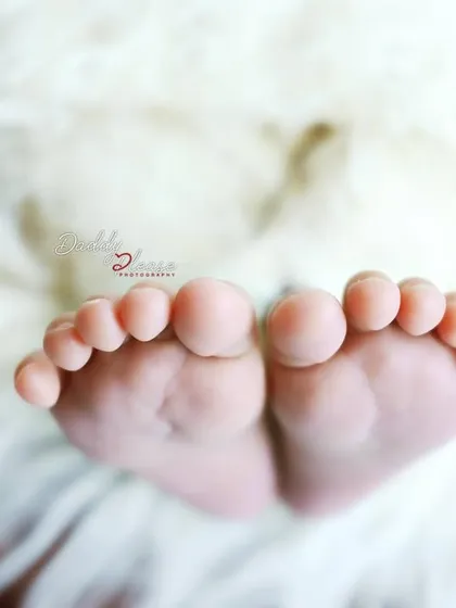 A macro shot focusing on the tiny, perfect toes of a newborn baby against a soft, white fur background. I love capturing these small details that change so quickly.