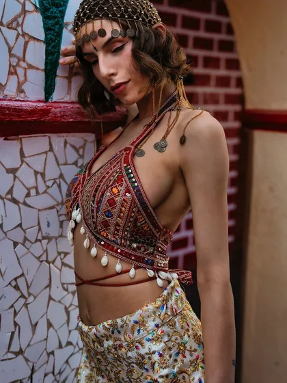 A bohemian look with intricate details. The projected background of a rustic brick wall adds texture and warmth, complementing the handcrafted feel of the top and headpiece.