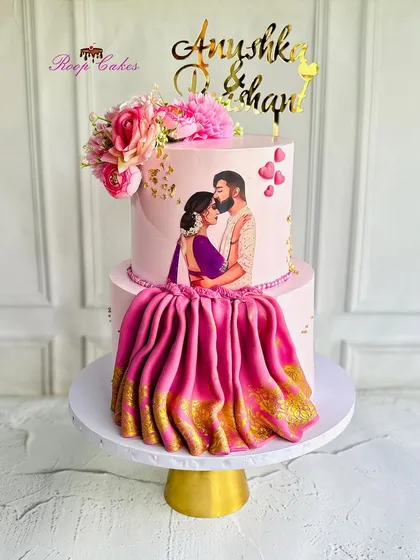 This engagement cake features a hand-painted edible portrait of the couple, making it incredibly personal. The design is completed with a flowing, realistic saree drape made from fondant with a golden border, blending artistry with tradition.