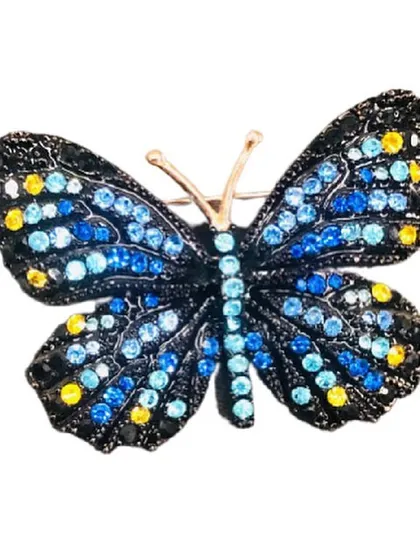 This striking butterfly brooch is fully embellished with multi-tonal blue and yellow crystals on a black metal base. It's a perfect statement piece to add a pop of color to any outfit.