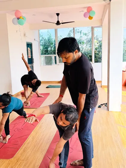 A hands-on correction in Trikonasana (Triangle Pose) helps with proper torso rotation and shoulder alignment, allowing for a deeper and more beneficial stretch.