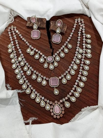 A grand, three-layered AD necklace set. This piece is designed for maximum impact, featuring square and teardrop stones, and is available in blue, green, pink, and red.
