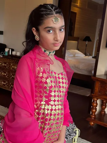 A close-up of the young client, showing the neatness of the front braids and the maang tikka.