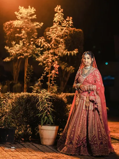 A beautiful outdoor portrait of the bride at night. The soft lighting and the garden background create a serene and romantic atmosphere.
