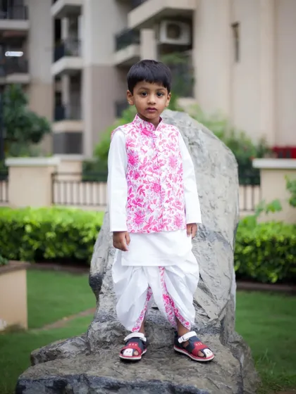 A classic portrait of a young boy in a stylish pink and white traditional outfit. We take posed shots that are perfect for framing.