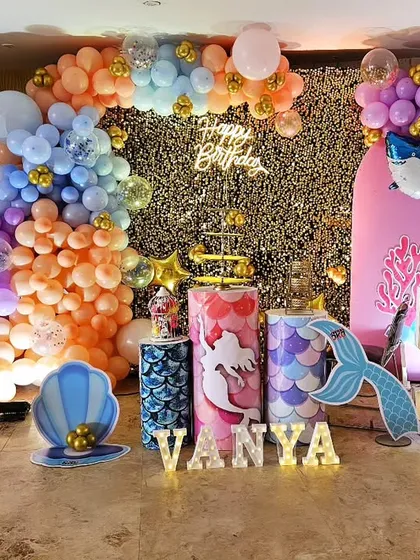 A magical mermaid-themed 5th birthday for Vanya. The decor is filled with under-the-sea elements like mermaid cutouts, shell props, marquee letters, and a stunning balloon arch in ocean colors.