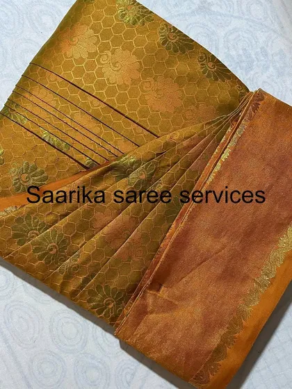 A mustard-colored brocade saree, folded to maintain its texture.