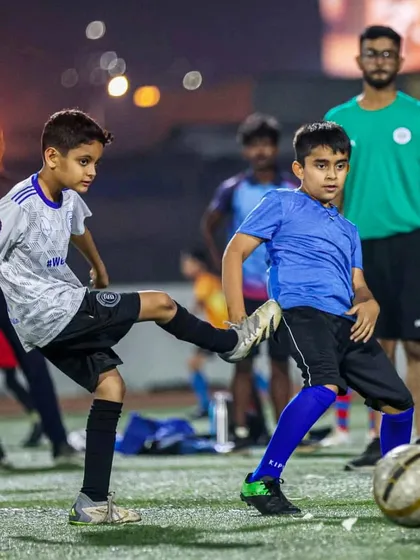 Passion, grit, glory. Two players battling for possession under the watchful eye of a coach.