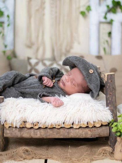 This little one is resting peacefully in our rustic-themed setup. We use natural textures and props like this miniature wooden bed to create a warm, timeless feel.