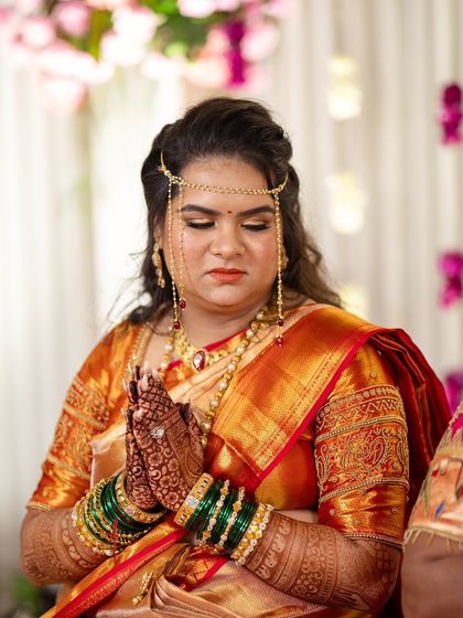 A moment of prayer and grace. This traditional Marathi bridal look features a mundavalya, intricate henna, and soft, glowing makeup.