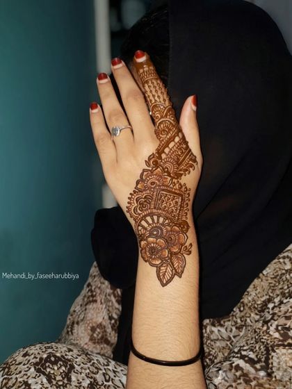 An intricate party henna design that covers just the index finger and a portion of the hand.