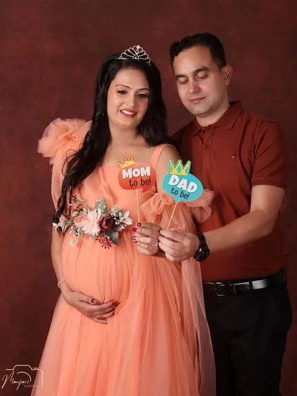 A fun and celebratory portrait. This couple uses props to announce they are becoming a 'Mom' and 'Dad', their smiles lighting up the frame.