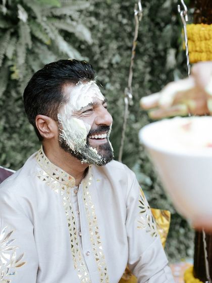 Covered in love and haldi! The groom's infectious smile captures the fun and playful spirit of this pre-wedding ritual.