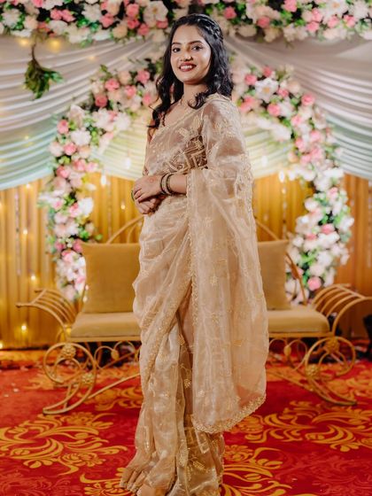 The bride posing elegantly on the stage, her sheer saree and soft makeup creating a beautiful silhouette.