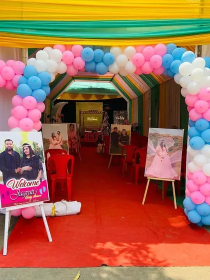 The entrance of a baby shower with a gender reveal theme, featuring a balloon arch and personalized welcome signs.