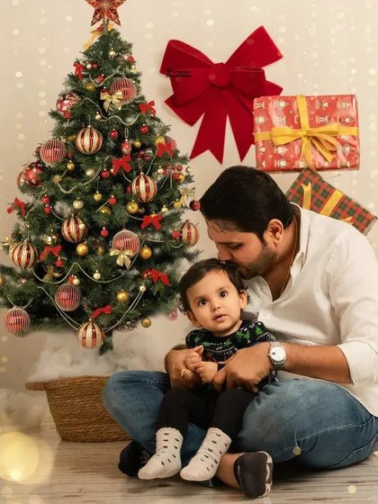 A tender moment between a father and his child in front of the Christmas tree. These quiet, loving interactions are just as important as the big smiles.