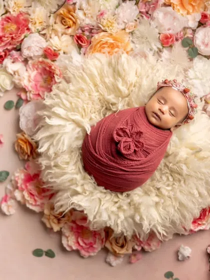 A beautiful baby blooming amongst the flowers. This overhead shot with a floral background creates a stunning, artistic portrait of a sleeping newborn.