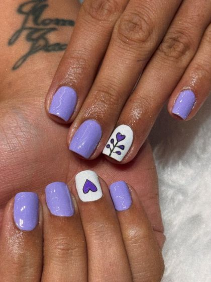 A cute and simple design on natural nails. This look features a soft lavender polish with a white accent nail adorned with a hand-painted heart and floral stem.