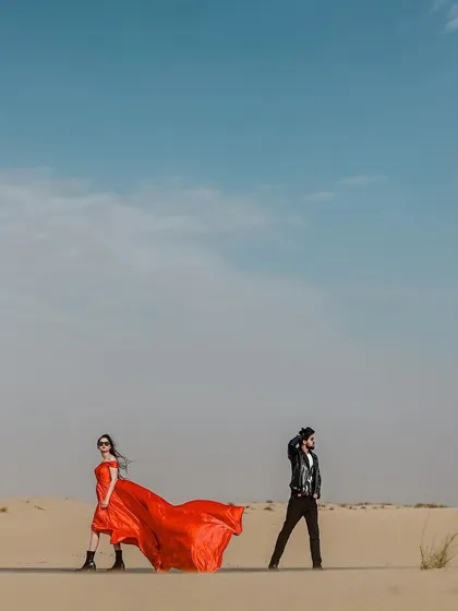 A wide-angle shot that emphasizes the scale of the Dubai desert. The couple stands apart yet connected, creating a visually interesting composition that feels both artistic and editorial.