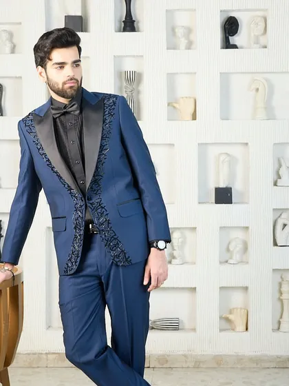 A full-length shot of a blue tuxedo with embroidered lapels, demonstrating how the intricate details create a cohesive and striking silhouette from head to toe.