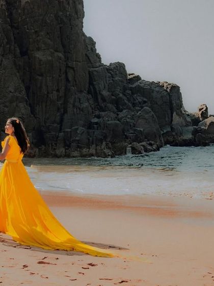 Walking along the beach into their forever. The long yellow trail of the gown adds a beautiful sweep of color to this pre-wedding photograph.
