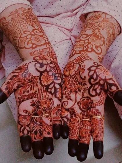 The dark, rich color of the henna paste on both hands, ready to be left on for hours to develop into a beautiful stain. The fingertips are fully covered, which is a bridal tradition.