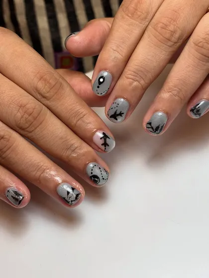 This client was heading to Switzerland and wanted her nails to tell the story. I hand-painted tiny airplanes, mountain silhouettes, and map routes on a cool grey base to capture her travel excitement.