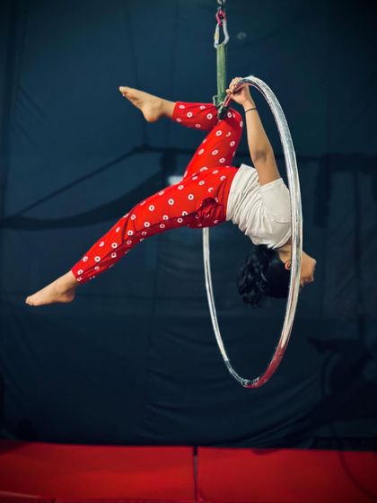 This dynamic pose shows a student moving through the hoop, demonstrating flexibility and control in a back-arched position.