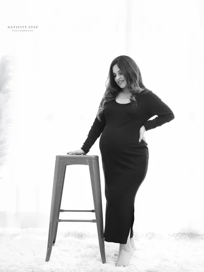 A simple and elegant black and white portrait. The high-key lighting and minimalist setting put all the focus on the mother-to-be and her beautiful silhouette.