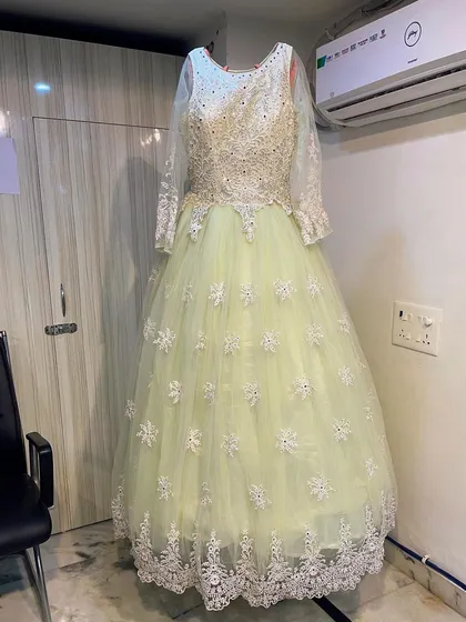 Make a fairy-tale entrance with this pastel lime ballgown. The bodice is adorned with detailed white floral embroidery and beadwork, flowing into a full tulle skirt that's both elegant and perfect for a reception or formal event.