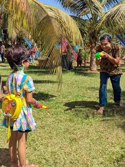 A father and daughter share a fun moment during the Holi water fight. Our farm events are designed for families to connect and enjoy themselves in a natural setting.