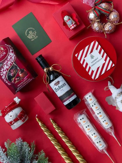 A deconstructed view of the 'Santa's Sweet Retreat' hamper, showing the variety of chocolates, wine, and festive decor.